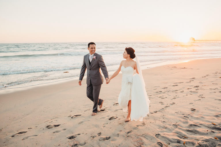 bride and groom walking on beach at sunset