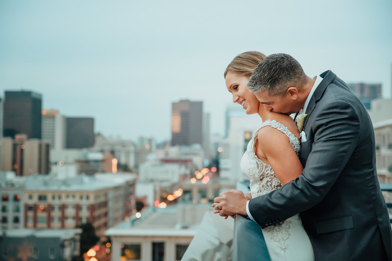 bride and groom on roof of building in city