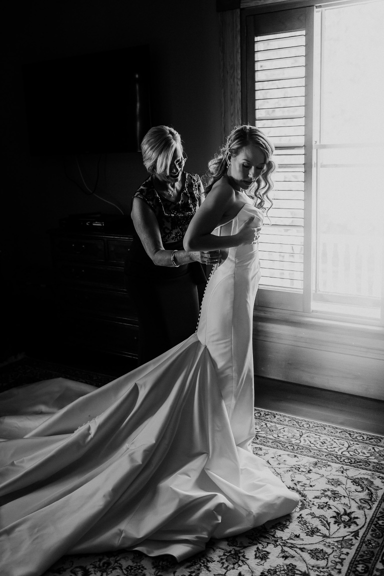 mother helping bride into dress