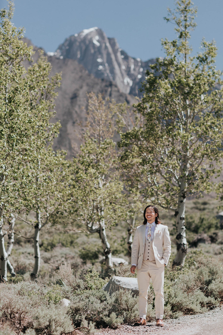 a groom stands in aspen grove in front of mammoth mountain