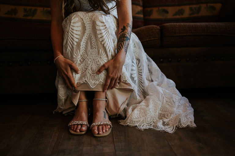bride's tattooed arms reaching down to pull her dress up and show her shoes