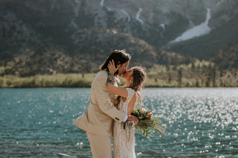 bride and groom kiss in front of convict lake in mammoth