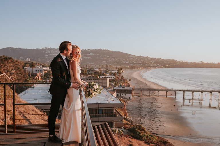 bride and groom on a deck at Martin Johnson House wedding overlooking the Scripps Pier and beach in La Jolla