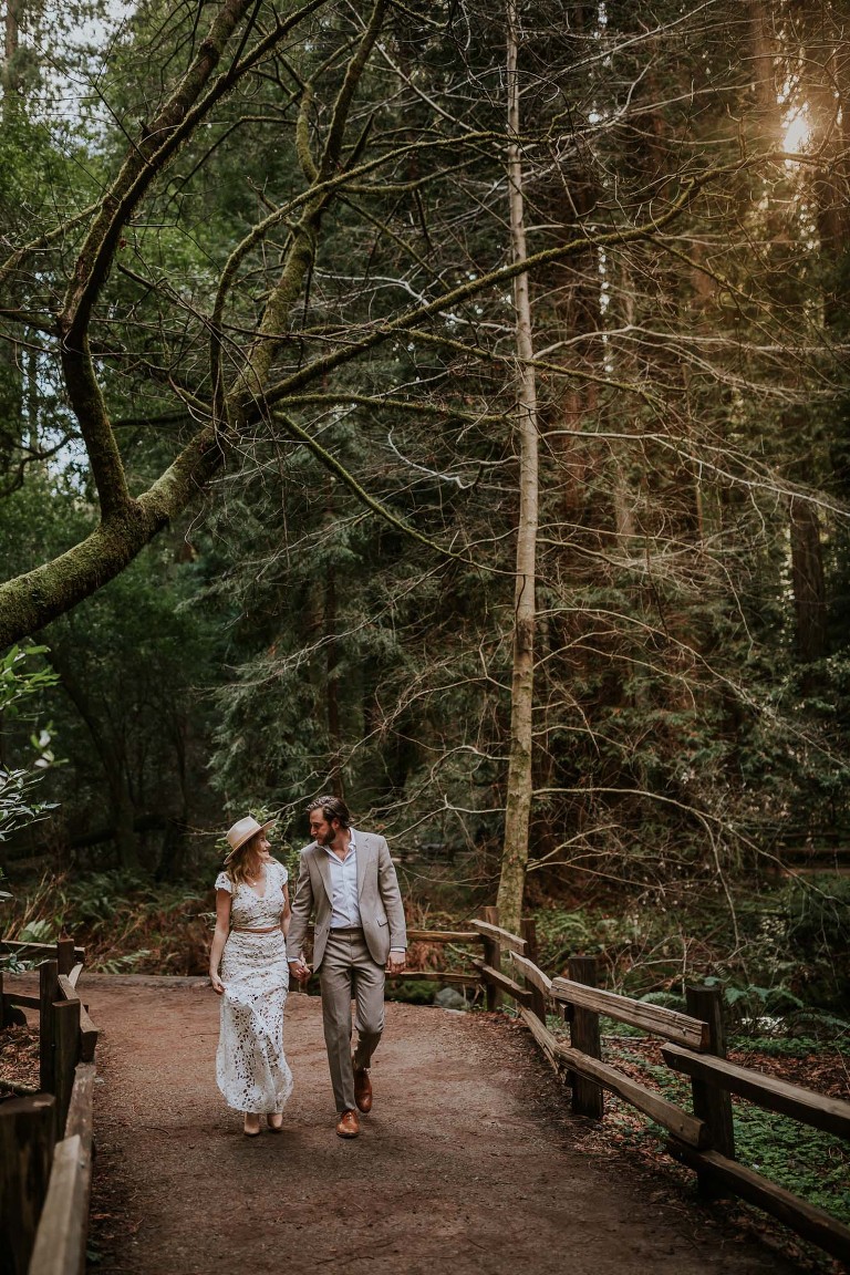 couple walking along trail in redwood forest for muir woods engagement session