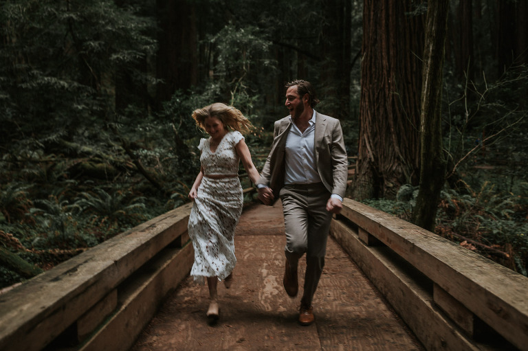 couple running across bridge in forest