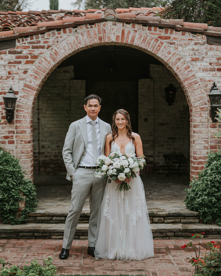 bride and groom in front of spanish style house