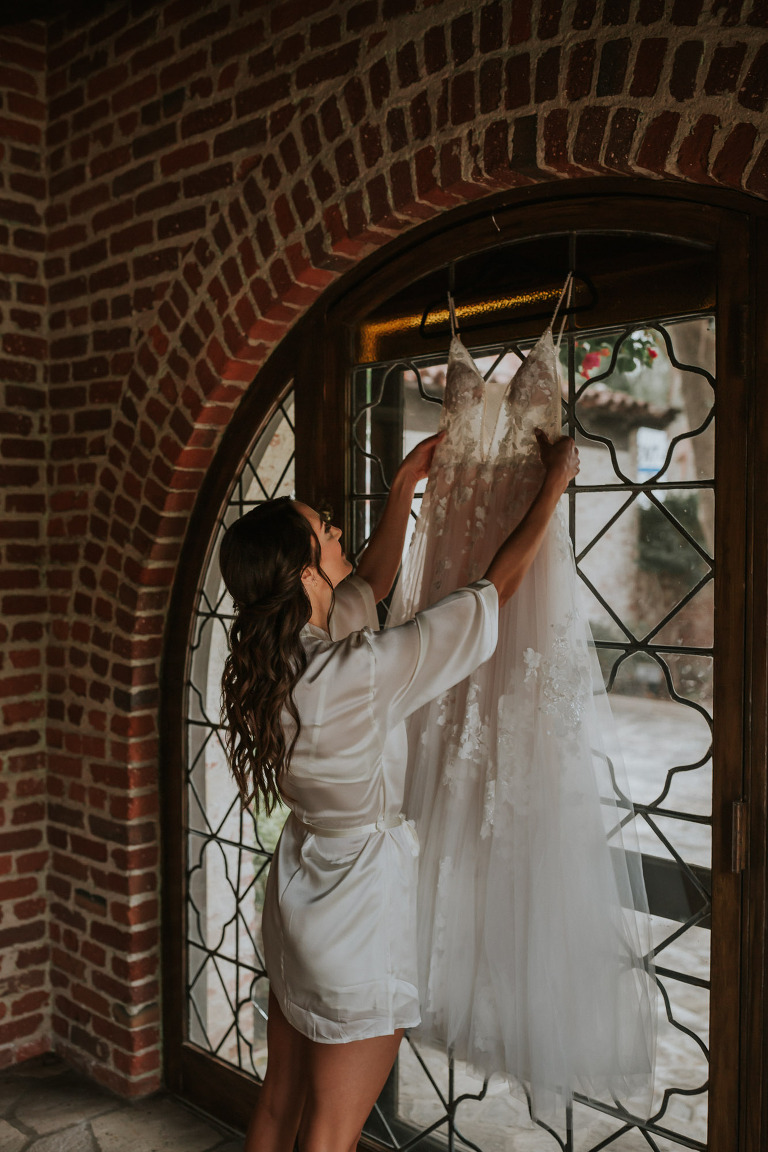 bride reaching for her hanging dress