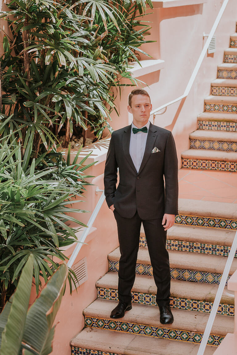 groom standing  on pink tiled stairs of la valencia