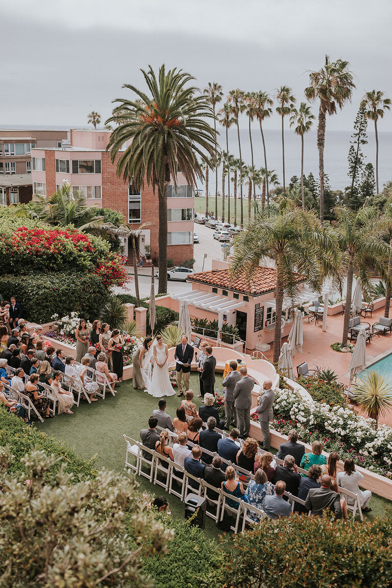 overlooking the wedding ceremony at la valencia hotel with the palm trees and coast in the background