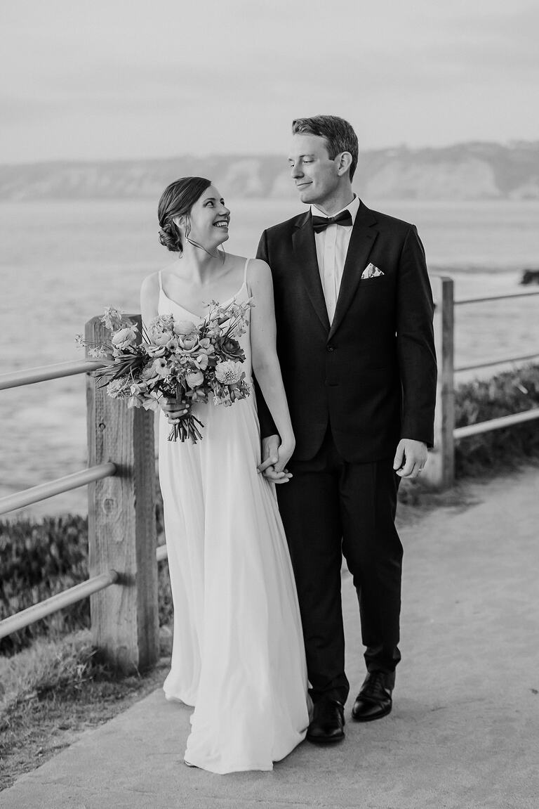 bride and groom walk along the oceanfront at la valencia wedding